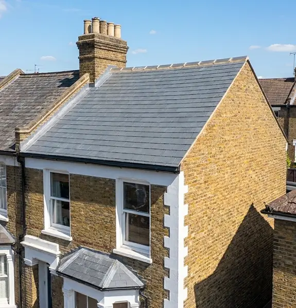 New grey tiled roof alongside the old worn roof it replaced